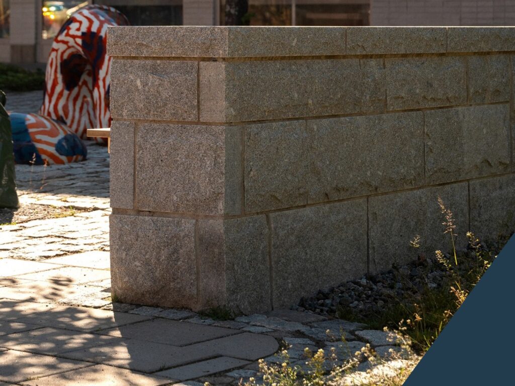 Murbeklädnad i granit med råkopp och hörnsten på Skogås Torg