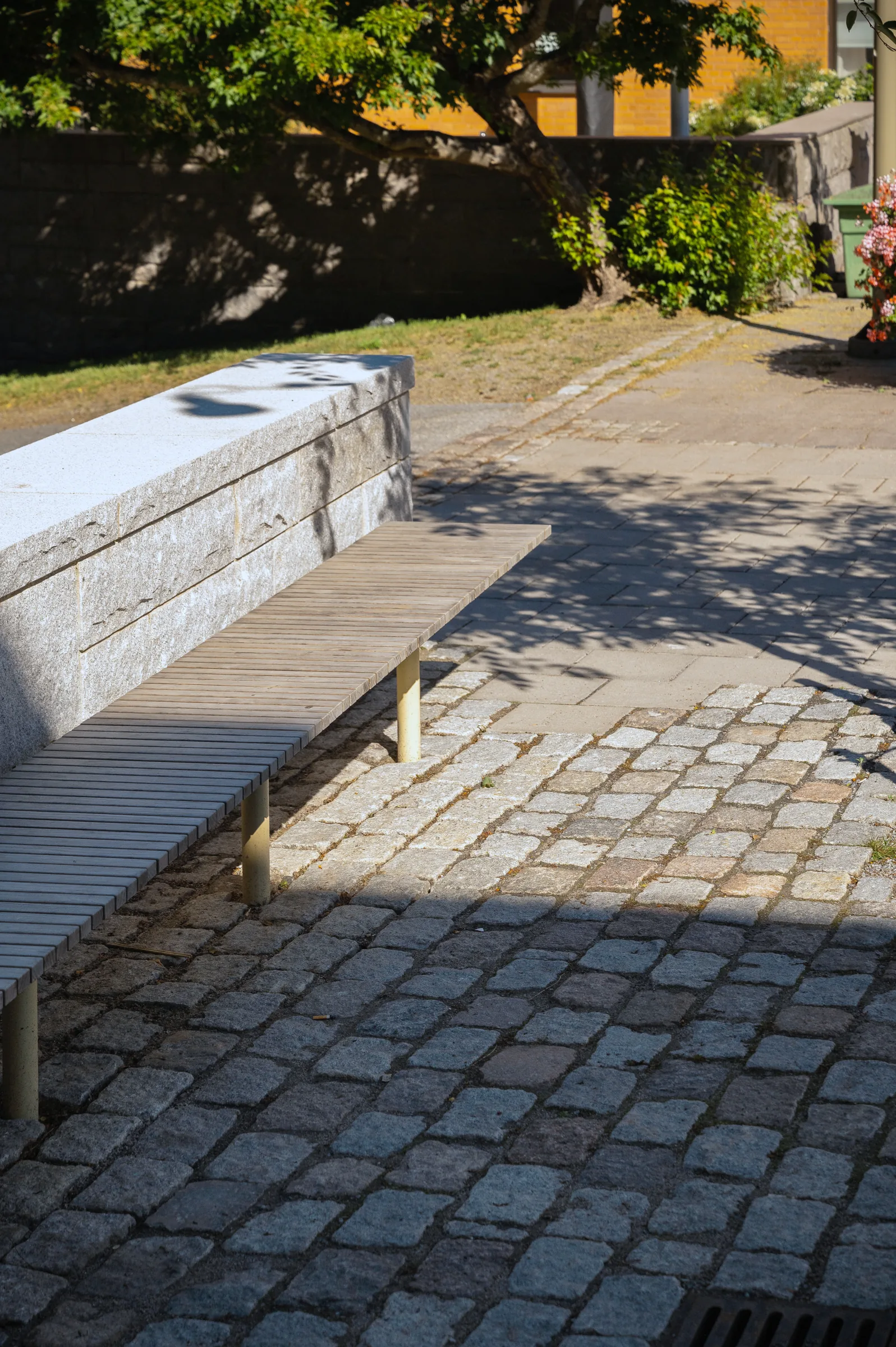 Återbrukad storgatsten i granit vid sittmur på Skogås torg