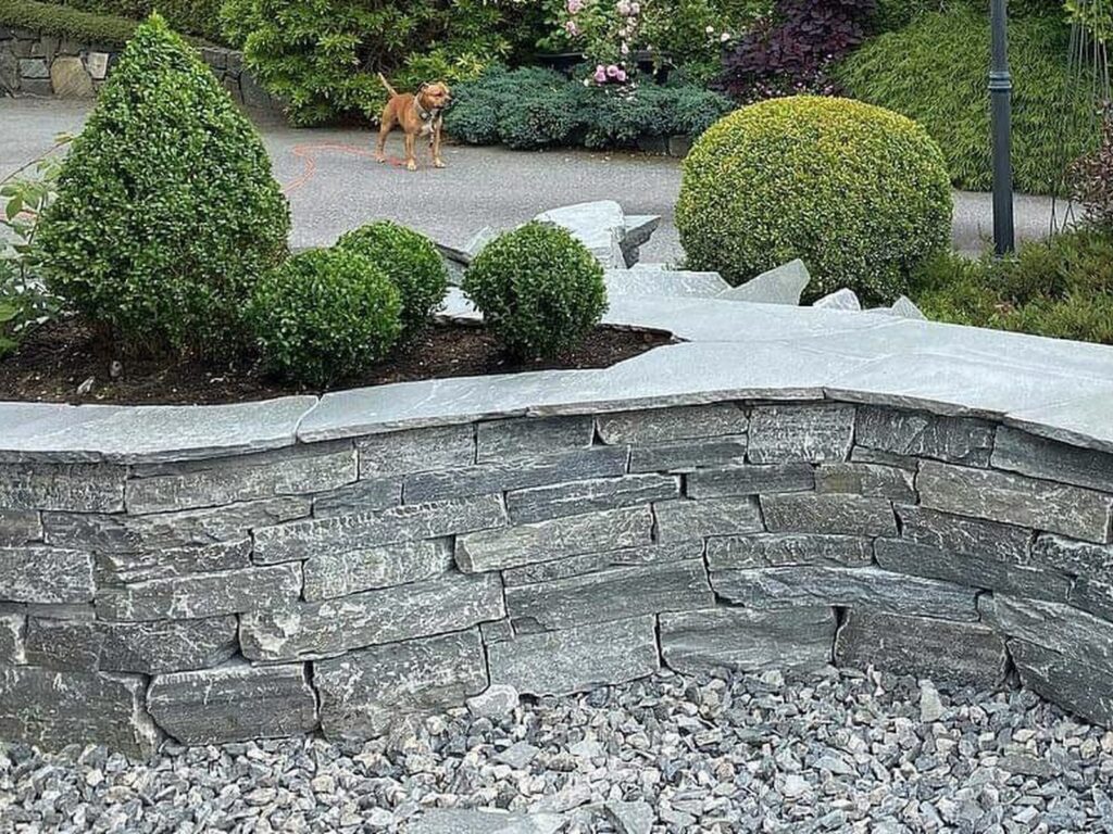 Montering av mur i natursten, torrmur av Altaskiffer runt en plantering